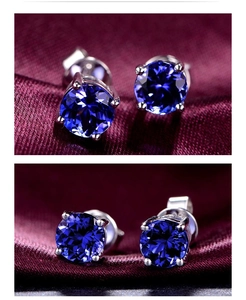 Detailed view of round cut blue gemstone stud earrings in silver four-prong setting