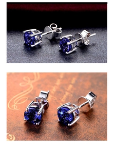 Macro detail of silver stud earrings featuring deep blue round gemstones in four-prong settings
