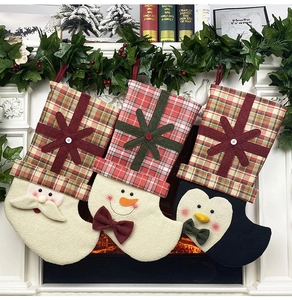 Three festive Christmas stockings featuring Santa, Snowman and Penguin hanging on a fireplace