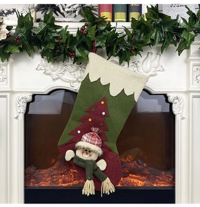 Detail of red and green felt Christmas stocking with plush snowman and tree on a fireplace