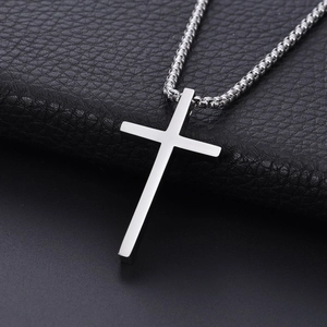 Detailed close-up of a polished titanium steel cross pendant on a silver box chain necklace