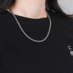 Gros plan détaillé d'un collier chaîne de blé tressé en argent sterling S925 sur un modèle