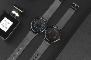 Close-up of minimalist black quartz watch with red and blue accents on metal mesh band