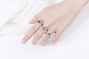 Detailed view of three silver rings with round moissanite stones on white silk