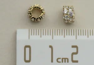 Detail view of a 14K gold plated 925 silver slider bead with zircon on a measuring scale