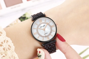 Close-up of black steel watch with white pearl dial, Roman numerals, and crystal bezel