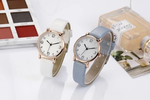 Detail view of stylish quartz watches with white and light blue leather straps and numeric dials