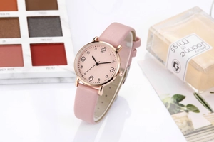 Fashionable women's quartz watch with pink leather strap and round gold case in lifestyle setting