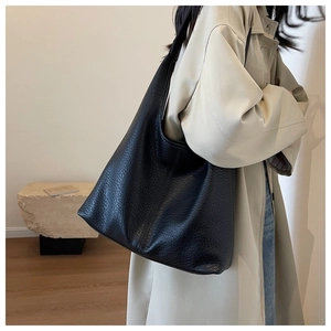 Lifestyle shot of large black leather tote bag with lychee texture on model's shoulder