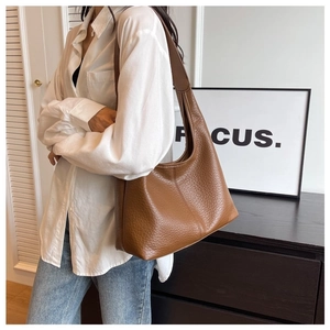 Close-up of caramel brown pebble leather hobo bag worn by a model in casual style