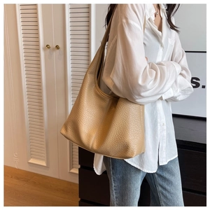 Close-up of model wearing apricot oversized hobo shoulder bag with litchi grain texture