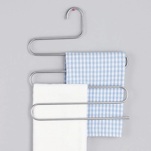 Detail of S-shaped stainless steel multi-layer pants hanger with towels on a grey wall