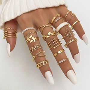 Close-up of a hand wearing a 9-piece gold butterfly and pearl rings set with white manicure