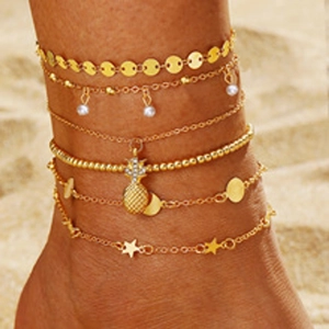 Close-up of golden multi-layer anklet set with butterfly and pearl on beach background