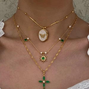Layered gold necklace set with butterfly shell pendant and green gemstone accents