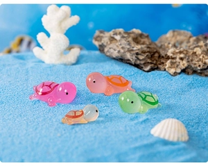 Luminous resin turtles in pink, orange, and green on blue sand with seashells