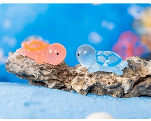 Close-up of orange and blue resin turtles on coral rock with blue sand for terrariums