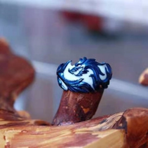 Close-up of a blue and white dragon pattern ring on a natural wood surface