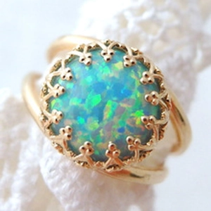 Macro shot of a vintage gold ring featuring a round blue-green fire opal in a crown setting