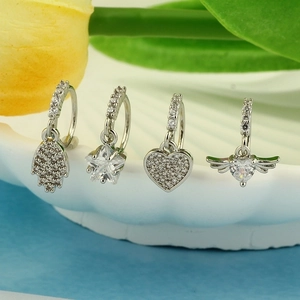 Macro shot of silver hoop earrings with Hamsa Hand and heart cubic zirconia charms