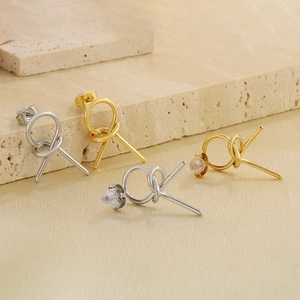 Detail of minimalist knotted hollow geometric earrings in gold and silver finishes
