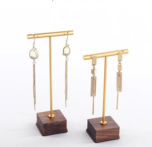 Macro detail of golden metal earring stand with walnut wood base for jewelry display