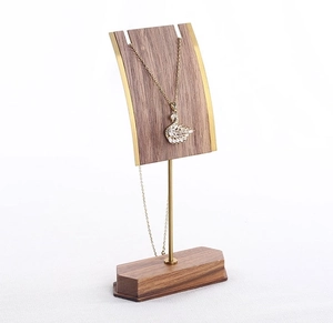 Detail of walnut wood jewelry stand with gold metal bar and swan pendant necklace