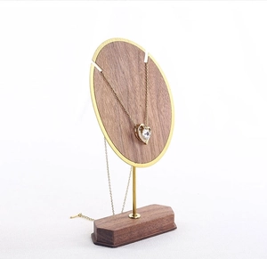 Detail of walnut wood and gold metal necklace stand with a heart pendant display