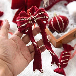 Red velvet Christmas bow ornament with gold trim held in hand for festive tree decoration