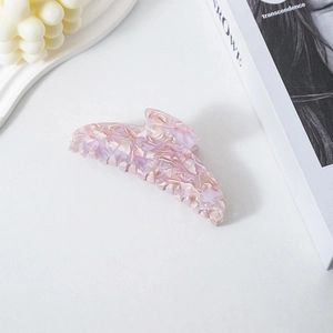 Pink marble texture acetate banana hair clip displayed with a white candle and book