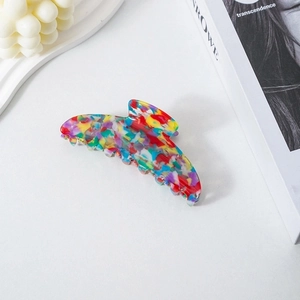 Close-up of crescent tortoise shell acetate hair claw clip with lifestyle props