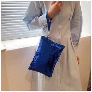 Detail of royal blue sequin clutch bag showing shimmering texture and leather wrist strap