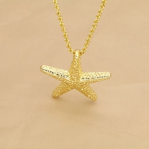Close-up of golden starfish pendant with detailed texture on silk background