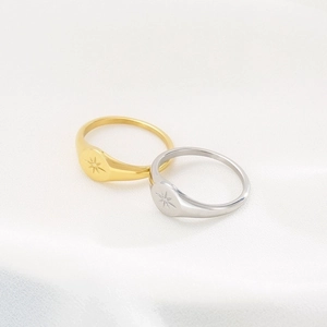 Detailed close-up of gold and silver starburst signet rings on white silk background