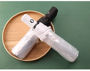 Detalle de paraguas plegables automáticos en blanco y negro con fundas de PVC transparente