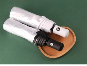 Primer plano de paraguas plegables automáticos blanco y negro en bandeja de madera de corazón