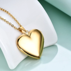 Polished gold heart locket pendant on O-chain displayed on a ceramic base