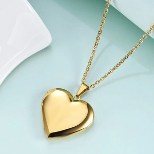 Detail shot of a polished gold heart-shaped locket pendant with a functional hinge
