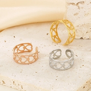 Detailed view of hollow heart rings in gold, silver, and rose gold on a stone base
