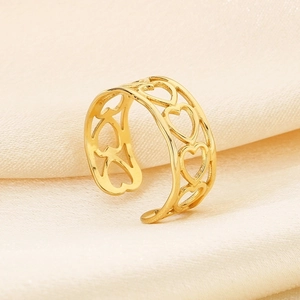 Macro shot of gold hollow heart ring on beige silk fabric showing delicate craftsmanship