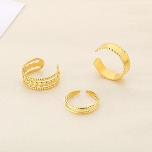 Three-piece set of minimalist hollow gold plated titanium steel rings on white fabric
