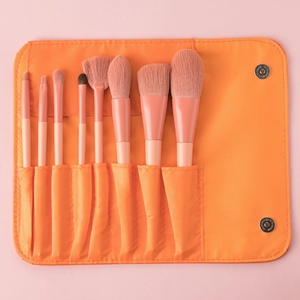 Detail of 8 pink makeup brushes organized in a roll-up orange storage case with snaps