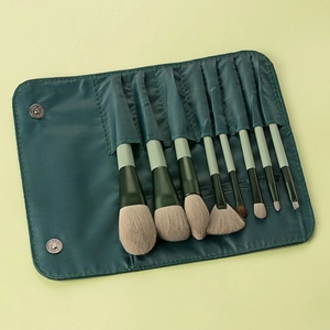 Detail view of 8 professional dark green makeup brushes in a matching folding travel case