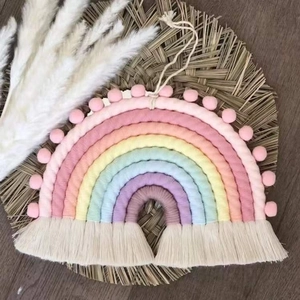 Detail of handmade woven rainbow wall hanging with soft pom-poms and tassels decor