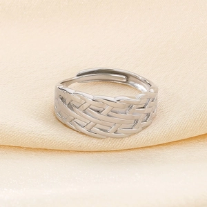 Detailed view of silver braided open ring with irregular leaf texture on silk fabric
