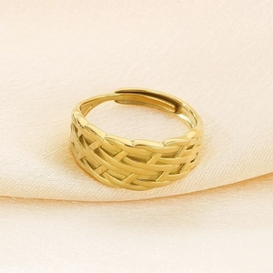 Close-up of golden crossover woven texture ring on elegant champagne silk backdrop