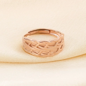 Close-up of rose gold woven ring with leaf texture on elegant silk background