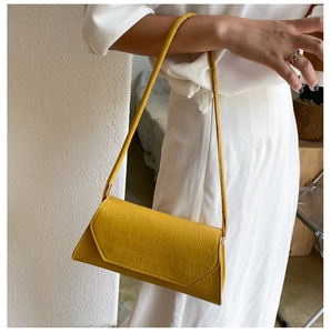 Detail of yellow crocodile embossed leather baguette bag with thin shoulder strap