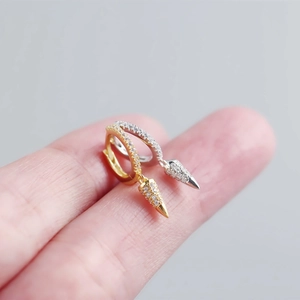 Macro view of geometric cone charms on silver hoop earrings with shimmering pave crystals