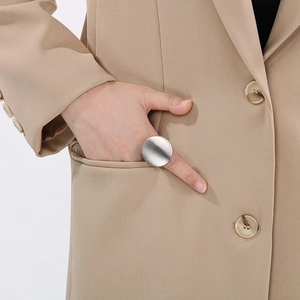 Detail of silver brushed metal round ring worn with a suit for a minimalist professional look